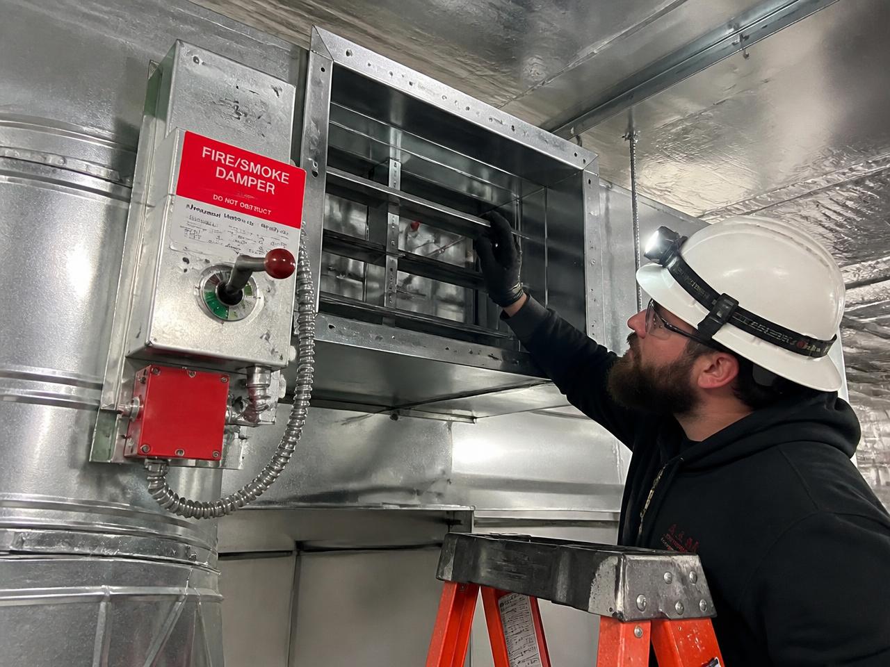 Technician inspecting a fire and smoke damper